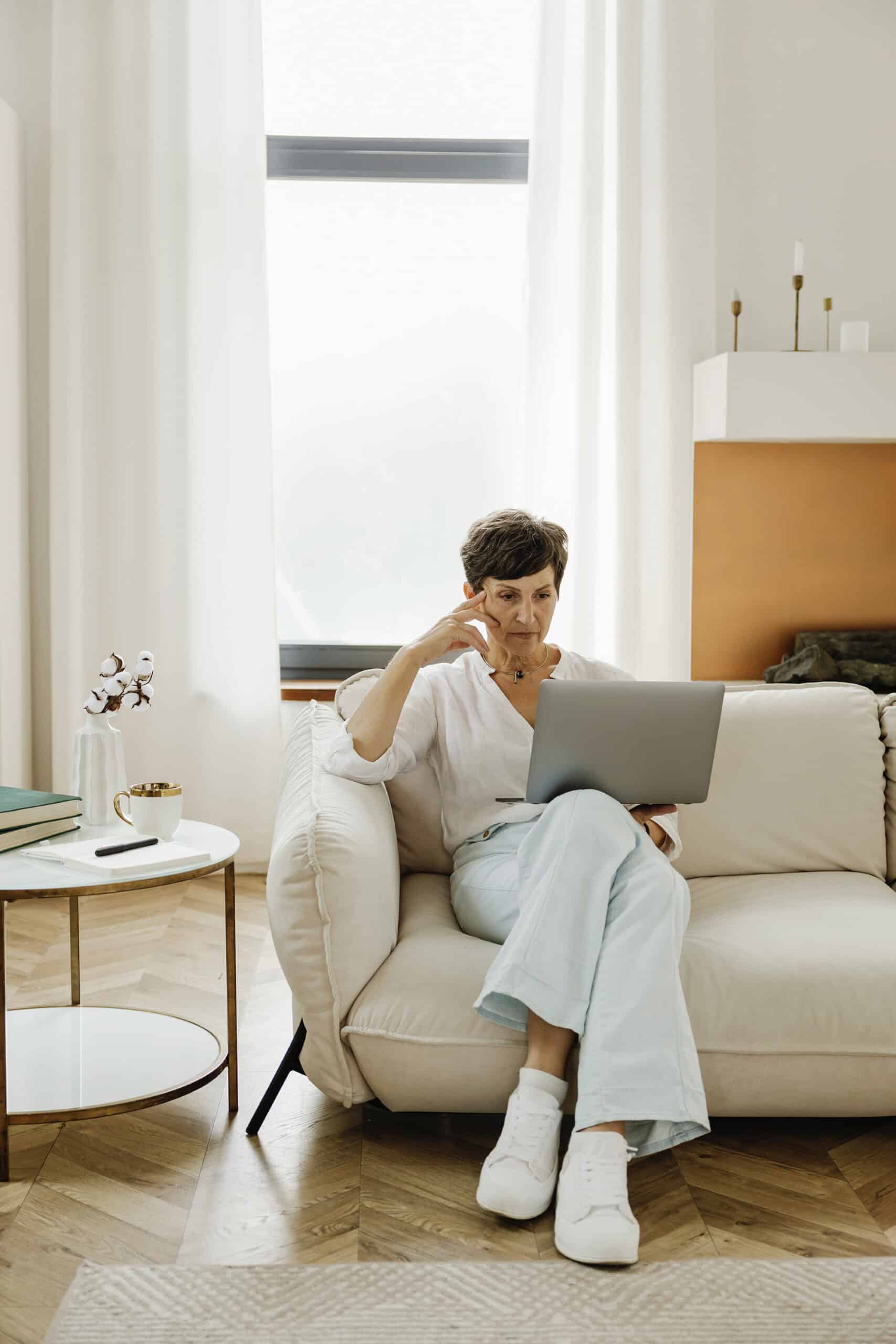A woman sitting on a couch and using a laptop.