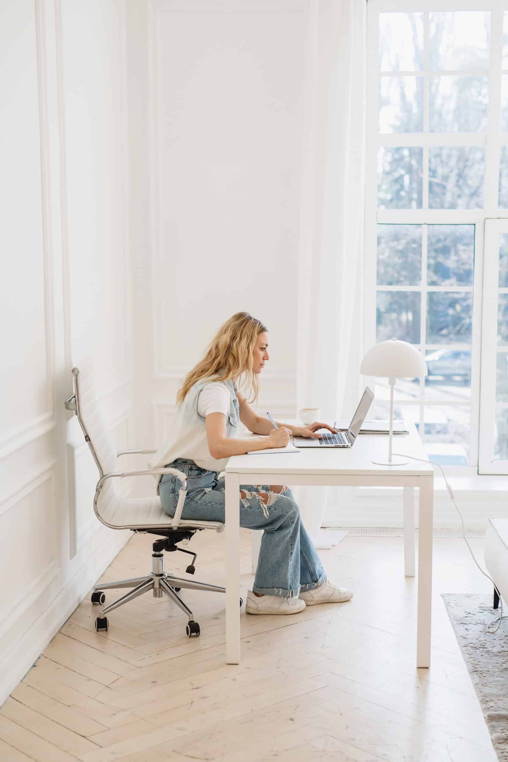 A woman working at her desk in a white room.